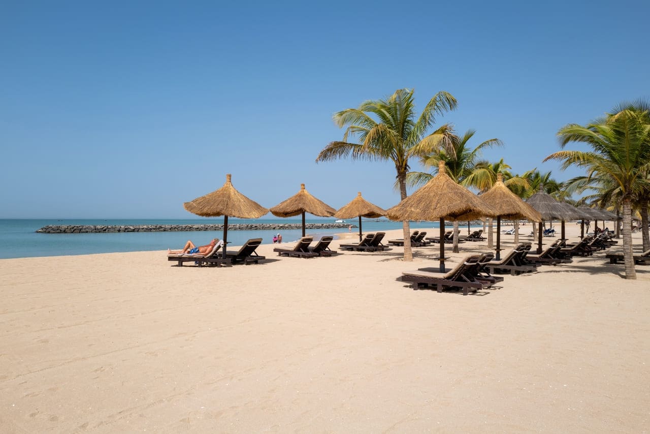 Tranquil escape under palm-fringed thatched huts by the sea.
