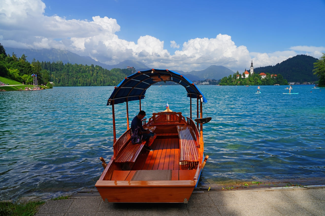 rystal-clear waters reflect the iconic church on the island, surrounded by alpine beauty.