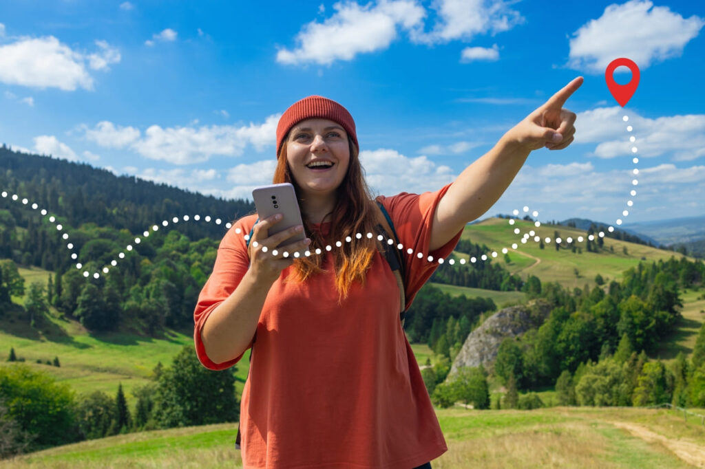 Smiling hiker using a phone and pointing toward a location pin in the hills.